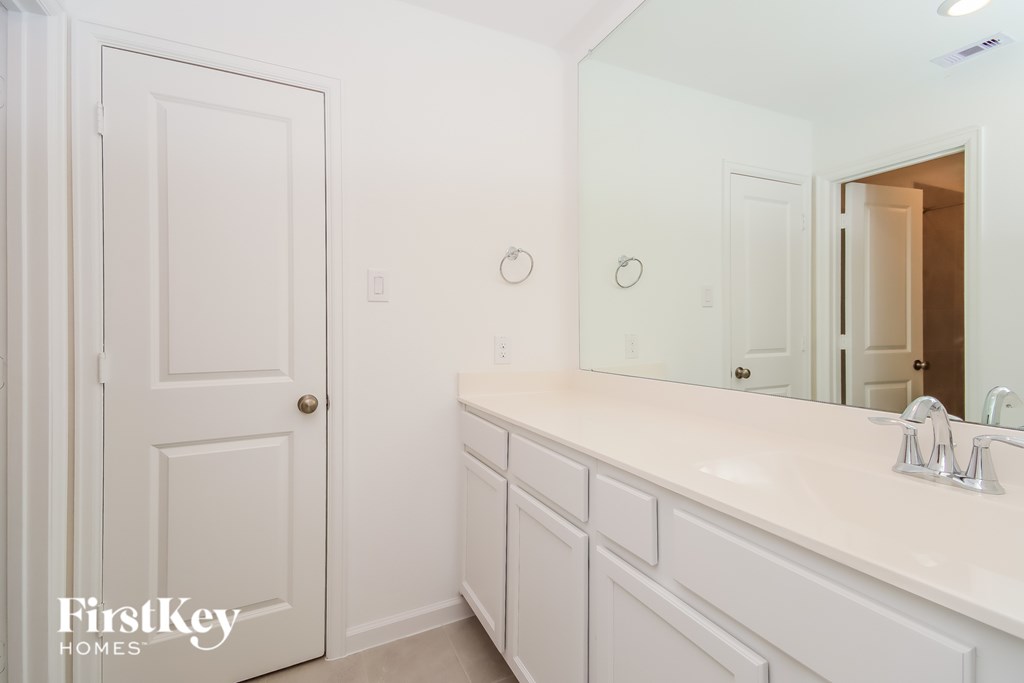 A white bathroom with a sink and mirror.