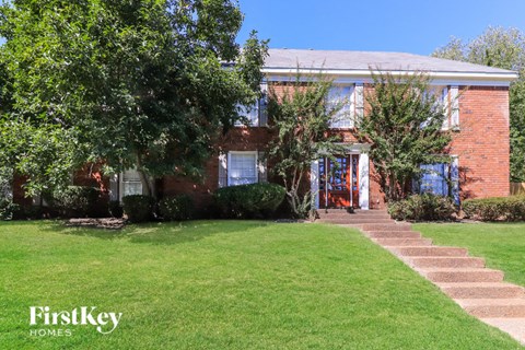 A brick house with a green lawn in front.