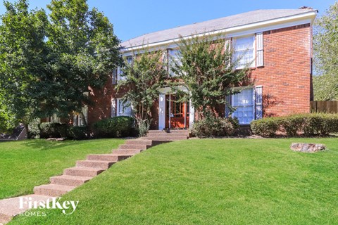 A brick house with a green lawn in front.