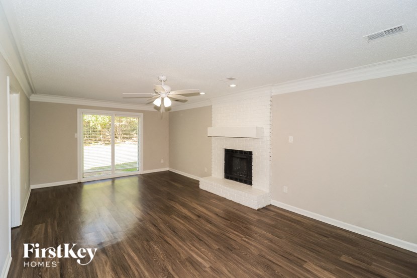 A spacious living room with a fireplace and a ceiling fan.