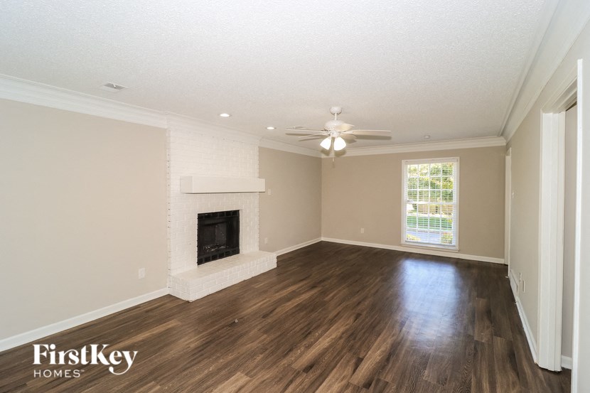 A spacious room with a fireplace and wooden floors.