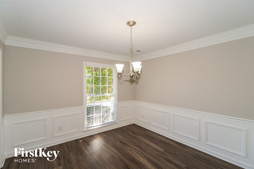 A well-lit room with wooden floors and a chandelier.