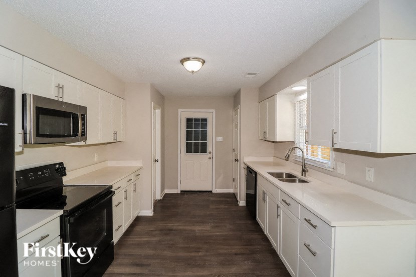 A kitchen with white cabinets and black appliances.