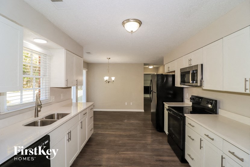 A kitchen with white cabinets and a wooden floor.