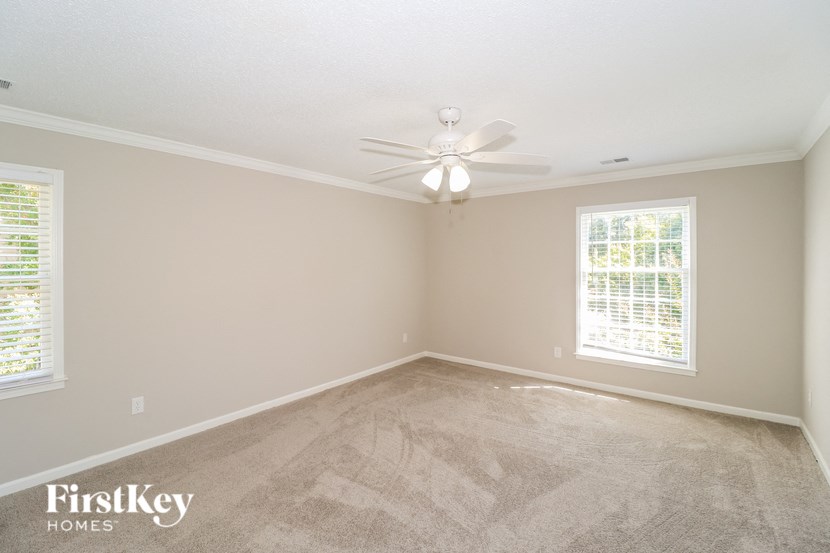 A room with a carpeted floor and a ceiling fan.