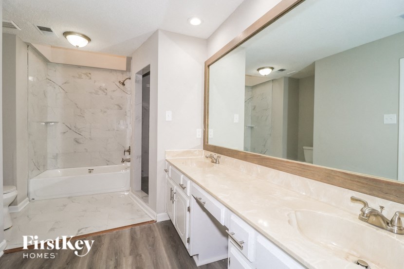 A bathroom with a marble wall and a wooden floor.
