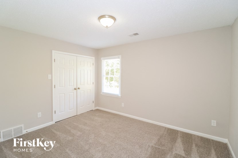 A room with a carpet floor and a door leading to a window.