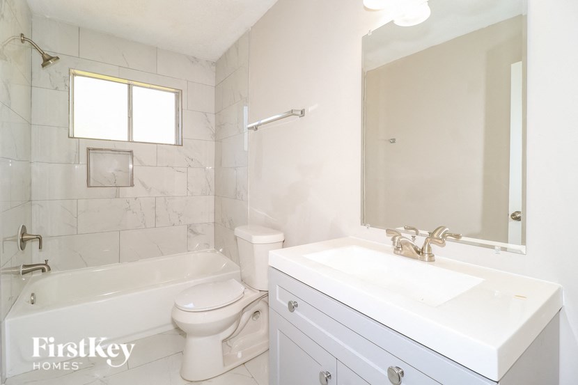A white bathroom with a tub, toilet and sink.