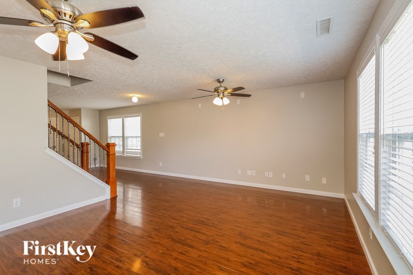 the living room and dining room with wood flooring and ceiling fans