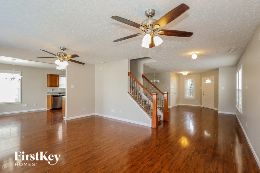 the living room and dining room with wood flooring and ceiling fans