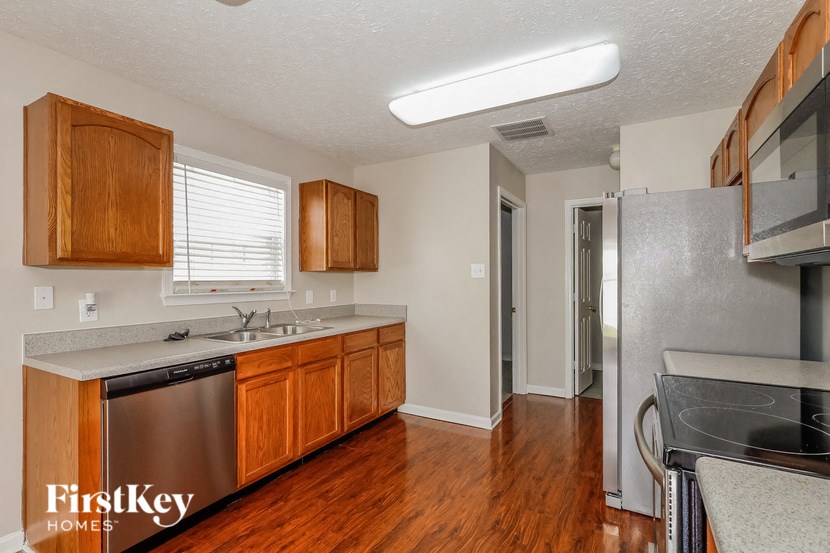 a kitchen with wood flooring and stainless steel appliances and a refrigerator