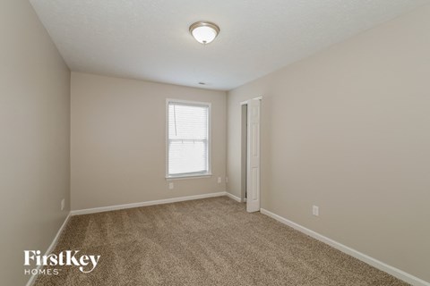 a spacious living room with carpet and a door to a closet