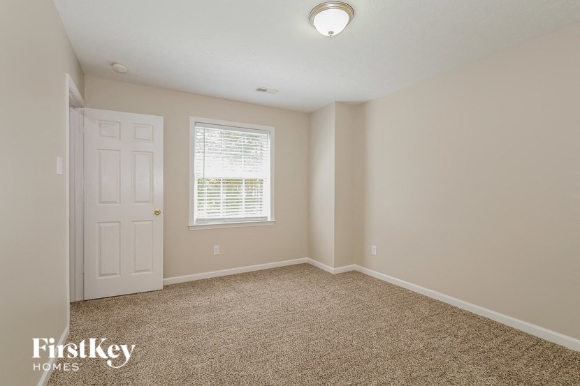 a bedroom with carpet and a white door and window