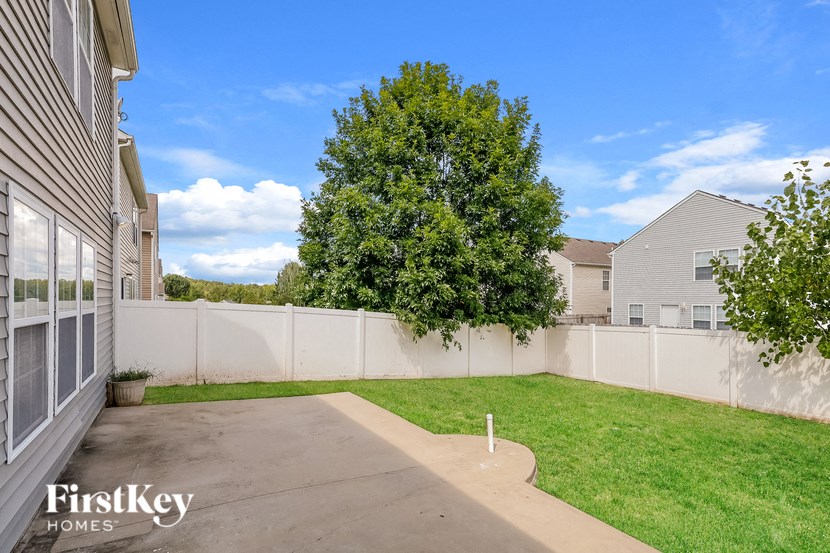 a backyard with a white fence and grass and a tree