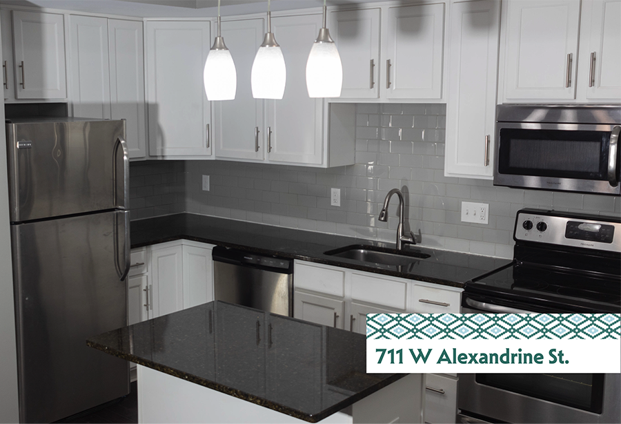 A kitchen with a black counter top and white cabinets.