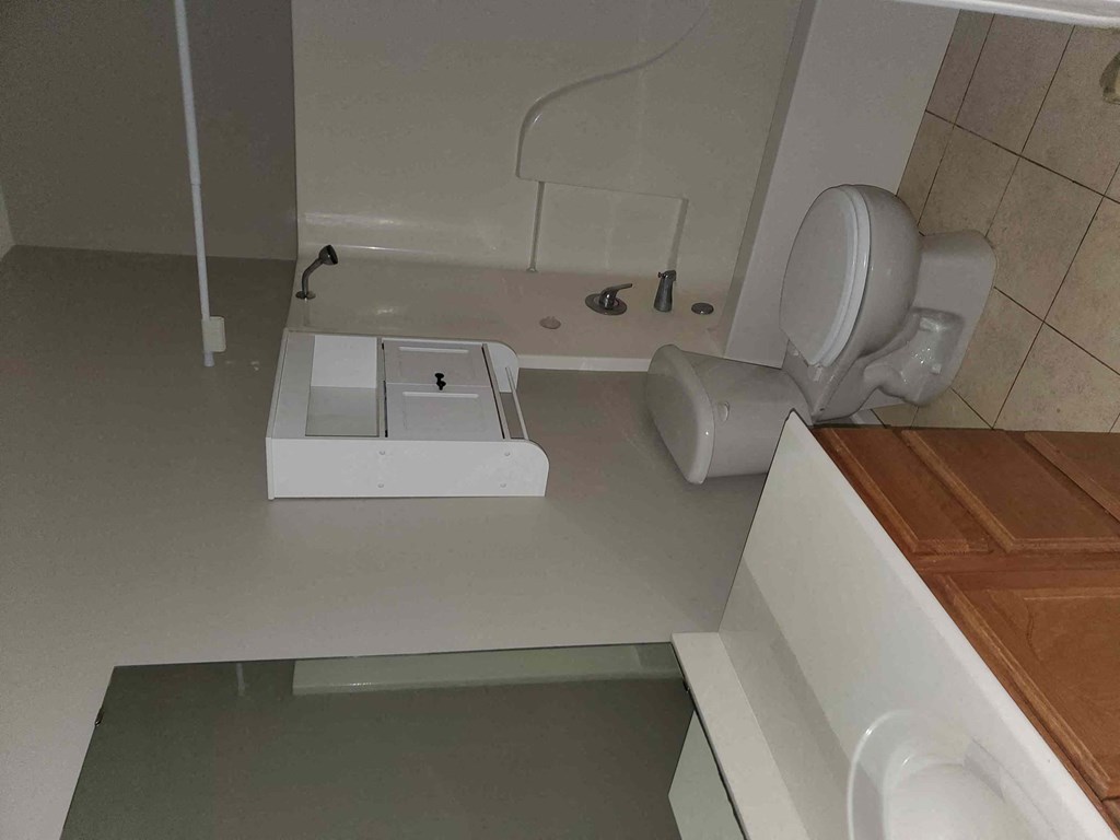 A white toilet is in a bathroom with a white sink and a white cabinet.