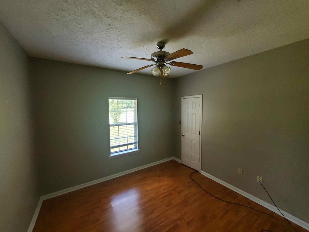 A room with a ceiling fan and a window.