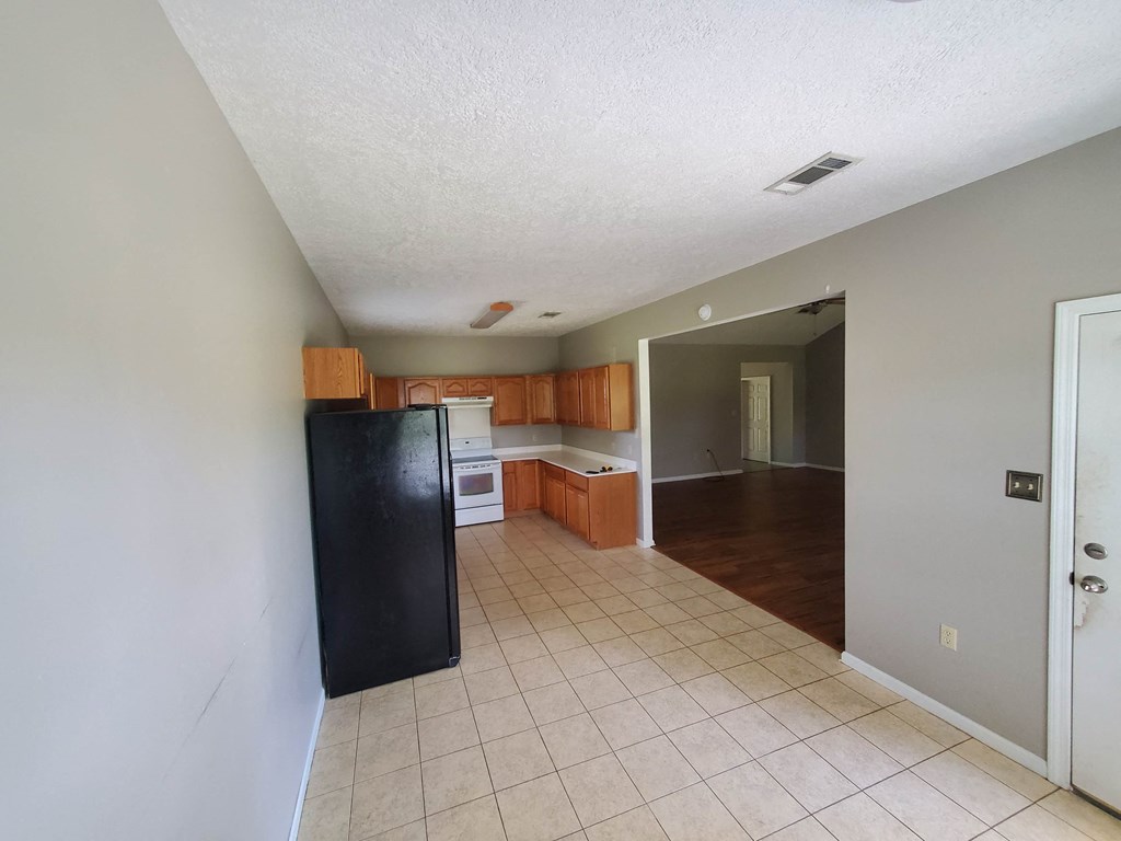 A kitchen with a black fridge and brown cabinets.