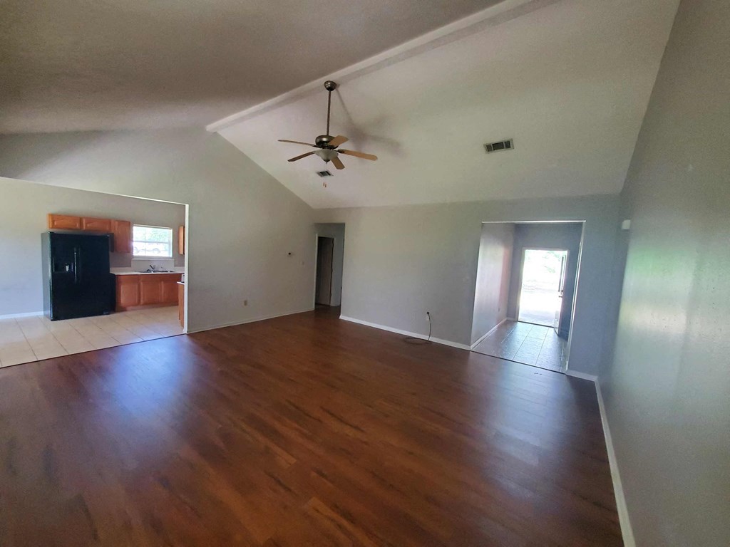 A room with a ceiling fan and wooden floors.