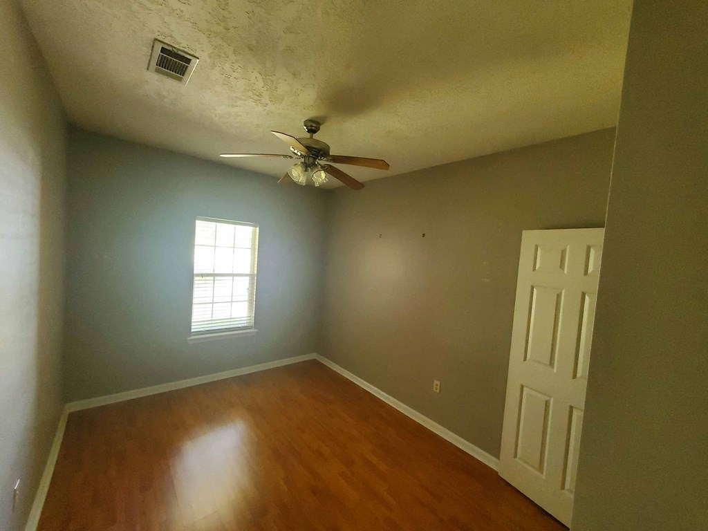A room with a ceiling fan and a door.