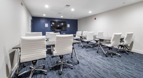 A conference room with white chairs and a blue carpet.