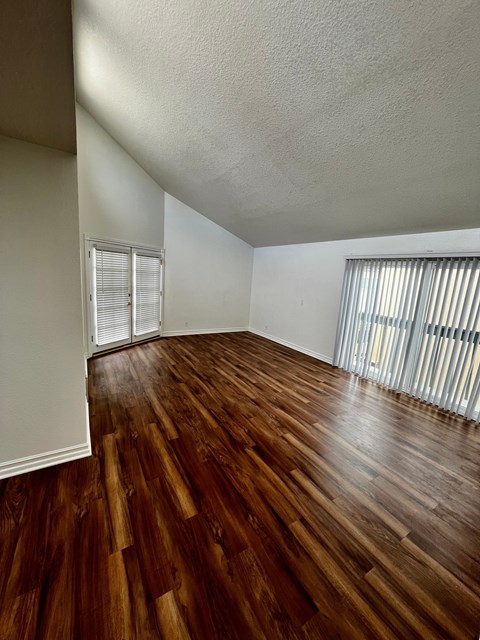 A room with wooden flooring and a window with blinds.