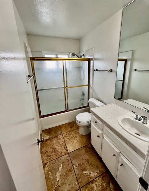 A bathroom with a toilet, sink, and shower.