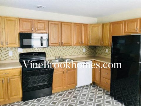 A kitchen with wooden cabinets and black appliances.