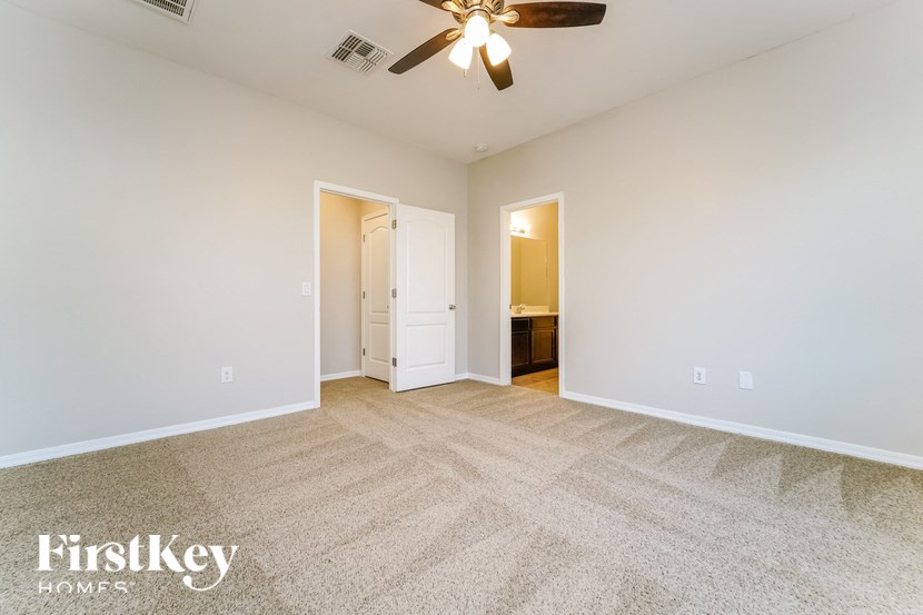 a spacious living room with carpeting and a ceiling fan
