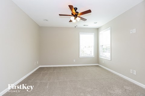 a spacious living room with carpet and a ceiling fan