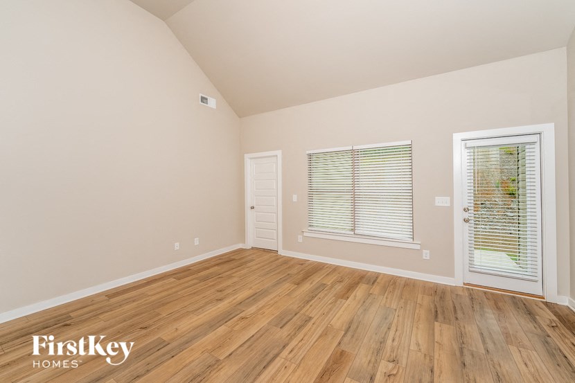 the living room of a home with wood floors and a large window
