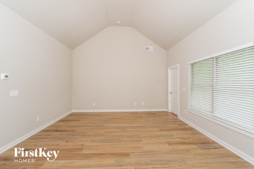 the upstairs bedroom with wood floors and a large window