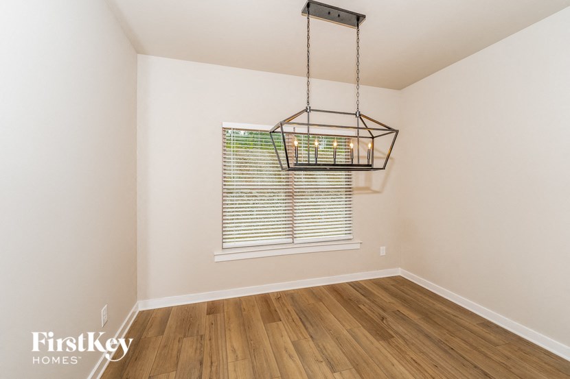 an empty living room with a window and a chandelier