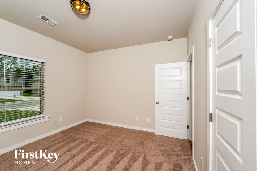 a bedroom with a door and a window and a carpeted floor