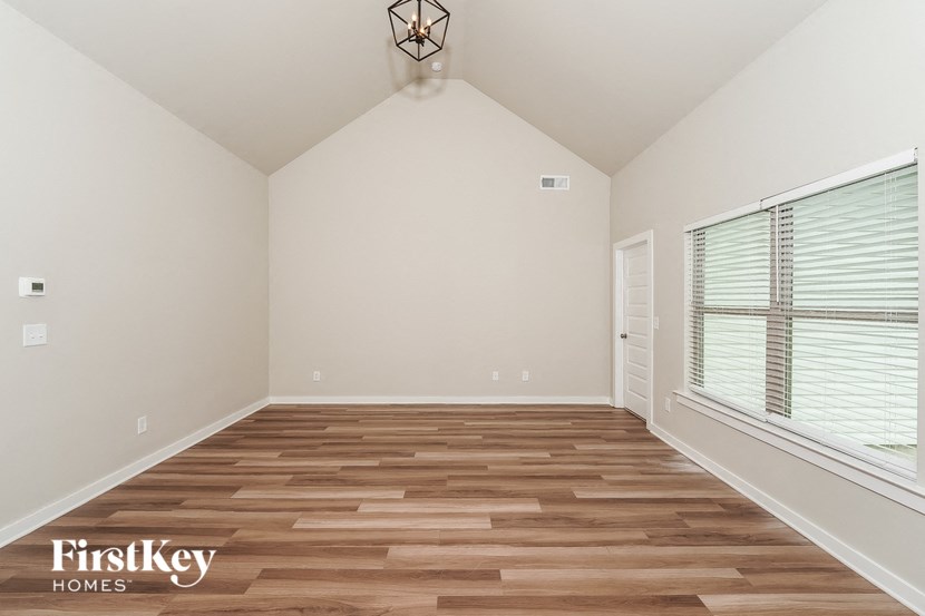 A room with wooden flooring and a window with blinds.