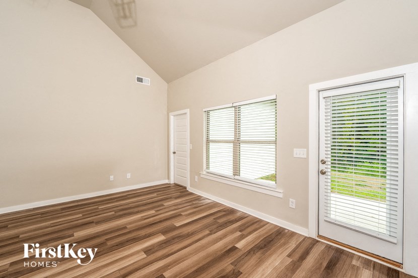 A room with wooden flooring and a window with blinds.