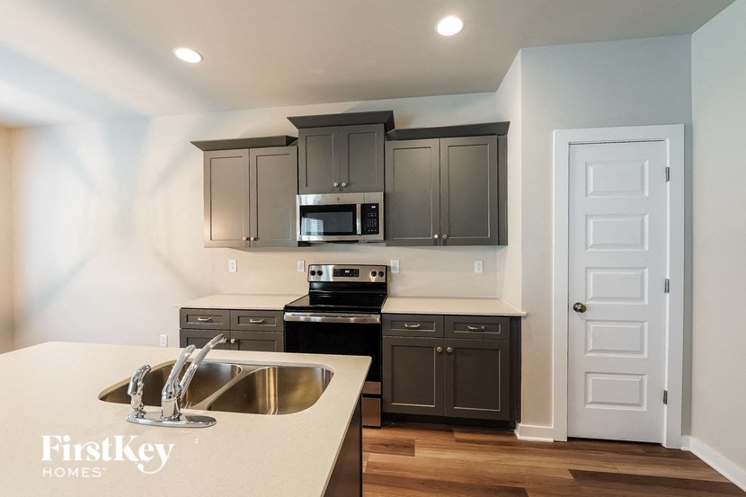 A kitchen with a sink, stove, and cabinets.