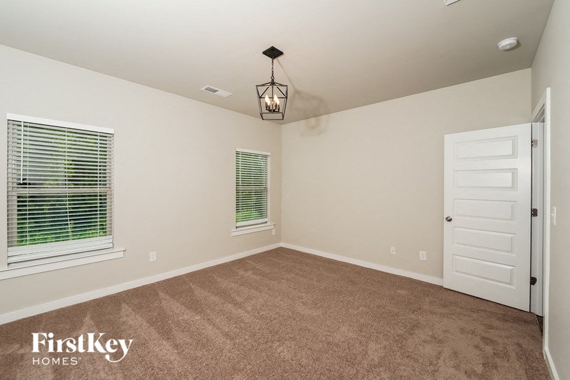 A room with a carpeted floor, a door, and a window with blinds.