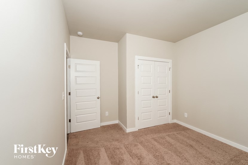 A bedroom with two doors and a carpeted floor.
