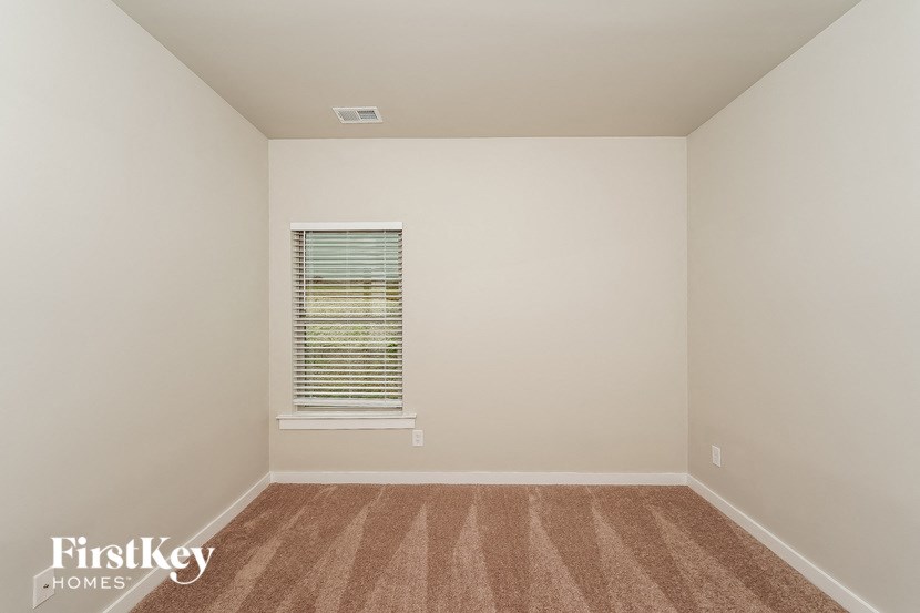 A room with a window and a carpeted floor.