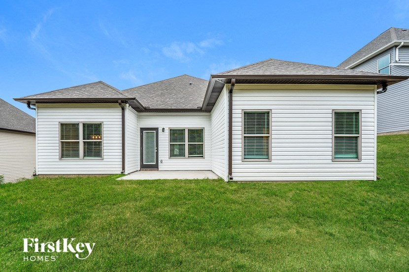 A white house with a black door and windows is for sale by FirstKey Homes.