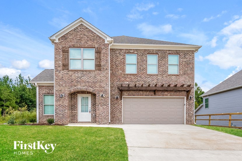 a brick house with a garage door and a lawn