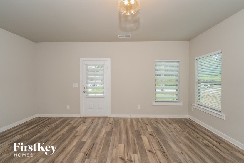 the spacious living room with wood flooring and a white door