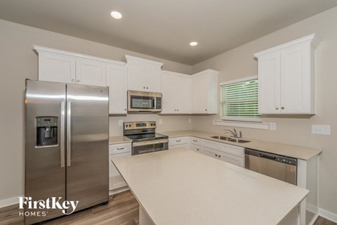 a white kitchen with stainless steel appliances and white counter tops