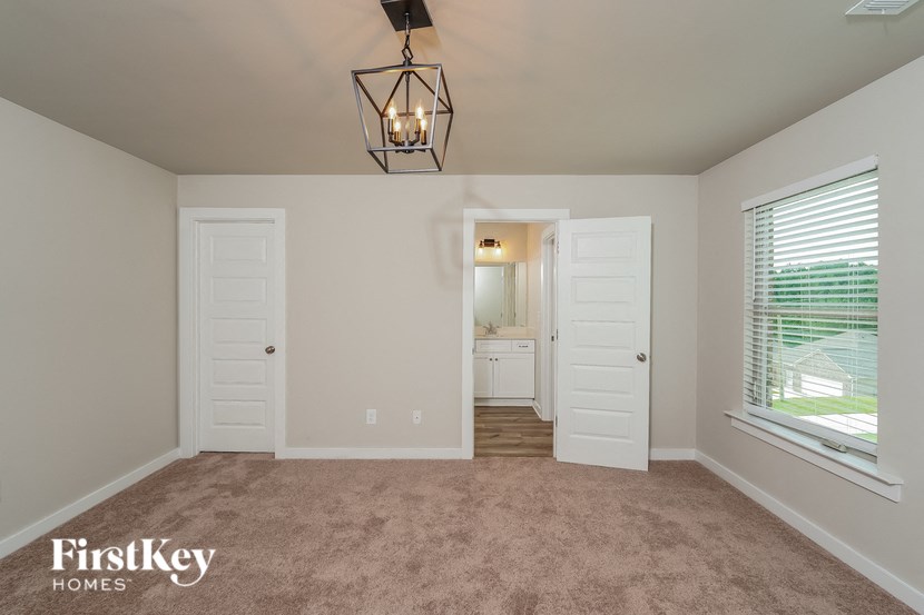 an empty living room with a window and a door to a bathroom