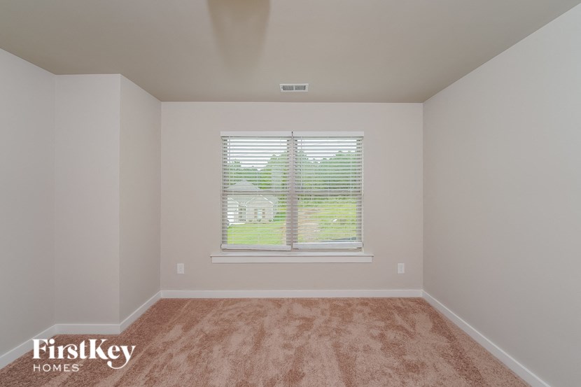 a bedroom with a window and carpeted floor