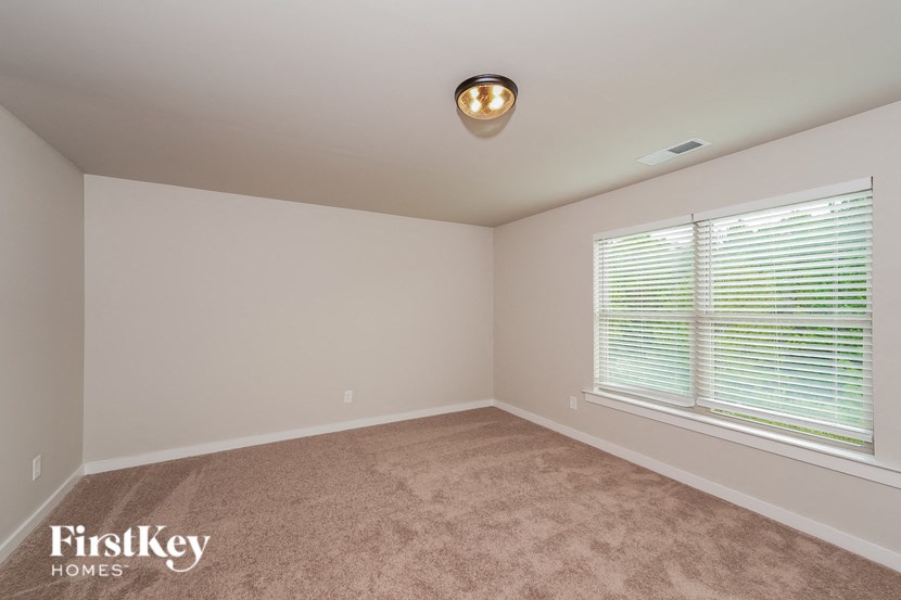 a bedroom with a large window and a carpeted floor
