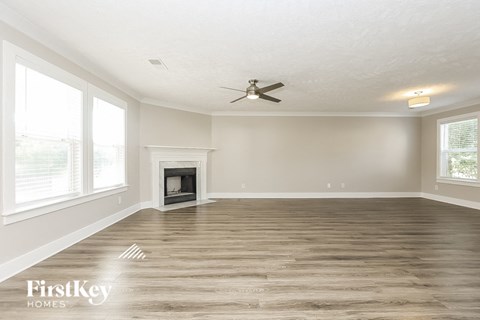 A spacious room with a fireplace and a ceiling fan.