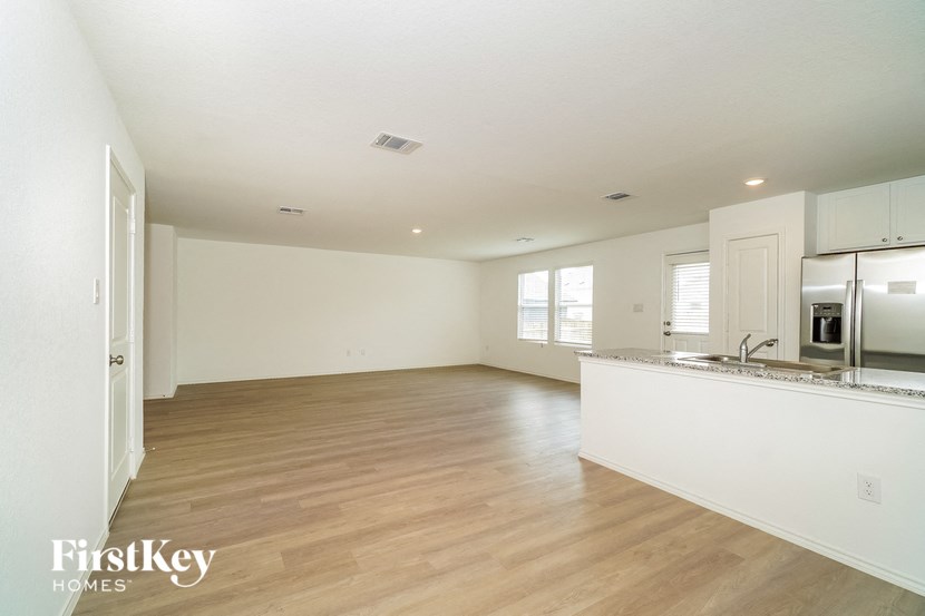 A spacious, empty room with wooden floors and white walls.