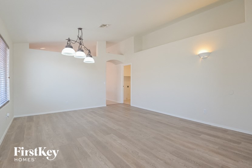 a spacious living room with white walls and wood flooring